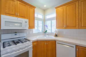Kitchen featuring white appliances, tile countertops, wood finish cabinets, and plenty of natural light