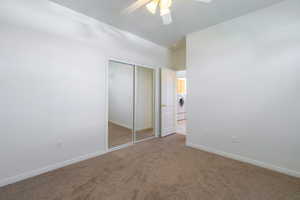 Unfurnished bedroom featuring a closet, carpet, washer / clothes dryer, and a ceiling fan