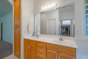 Full bathroom featuring double vanity, light carpet, and a walk in closet