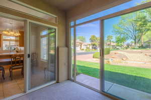 Doorway to outside featuring suspended lighting, carpet floors, and a residential view