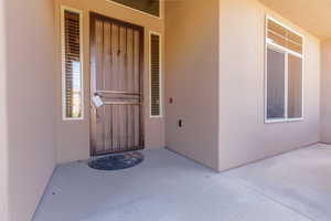 View of exterior entry featuring stucco siding and a patio area