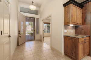 Foyer with light tile patterned floors and baseboards