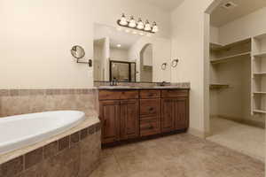 Bathroom with double vanity, a bath, a shower stall, and light tile patterned flooring
