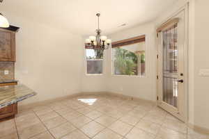 Unfurnished dining area featuring a chandelier and light tile patterned floors