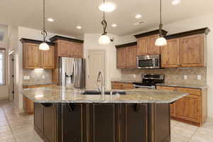 Kitchen featuring light tile patterned floors, light stone counters, and wood finish cabinets