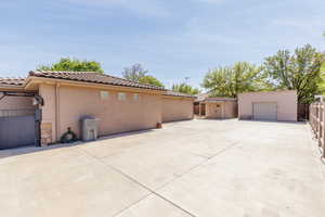 View of side of home featuring stucco siding, an outdoor structure, a tile roof, and a detached garage