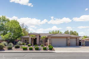 Mediterranean / spanish-style house featuring an attached garage, a tile roof, concrete driveway, and stone siding