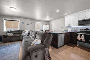 Kitchen with open floor plan, a peninsula, stainless steel appliances, a textured ceiling, and dual tone cabinetry.