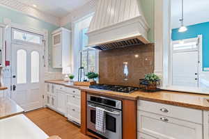 Kitchen featuring white cabinetry, stainless steel appliances, light wood-style floors, and light stone counters