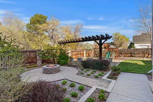 Fenced backyard featuring a fire pit, a patio area, and a pergola