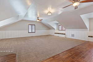 Additional living space featuring ceiling fan, lofted ceiling, hardwood / wood-style flooring, and carpet