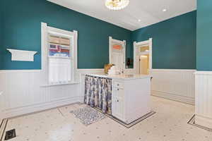 Interior space with a wainscoted wall, a chandelier, and light floors