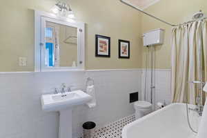 Bathroom with tile walls and a wainscoted wall