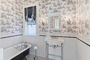 Bathroom with tile walls, wainscoting, a freestanding tub, and wallpapered walls