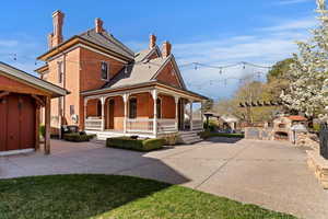 View of front of house with a chimney, a fireplace, brick siding, a large porch, and a patio