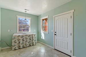 Entryway featuring a textured ceiling and light tile patterned floors