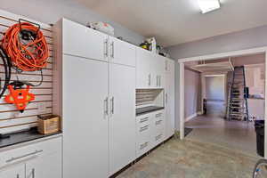 Kitchen with dark countertops, white cabinetry, and light flooring