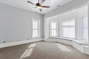 Carpeted spare room featuring a ceiling fan and baseboards