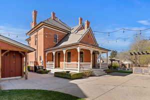 View of front of property featuring a chimney, a large porch, and brick siding