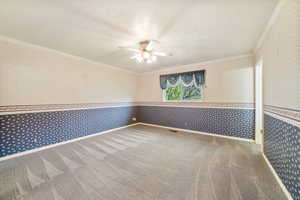 Empty room featuring wallpapered walls, ornamental molding, ceiling fan, light carpet, and a textured ceiling