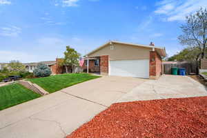 View of front of home with brick siding, a garage, and driveway