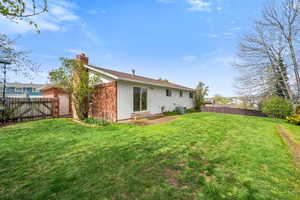 Back of property featuring a fenced backyard, a chimney, a gate, a patio, and brick siding