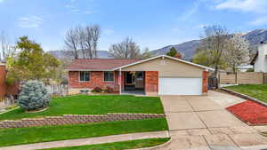 Ranch-style home featuring driveway, a mountain view, a garage, and brick siding