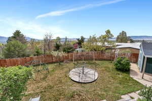 Fenced backyard featuring a mountain view, a patio, and a storage shed