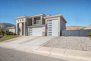 Contemporary house with stone siding, stucco siding, a garage, a balcony, and concrete driveway
