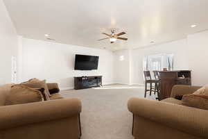 Living area with light carpet, ceiling fan, and recessed lighting