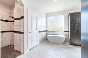 Full bath featuring a shower stall, a freestanding bath, tile walls, light tile patterned floors, and a wainscoted wall