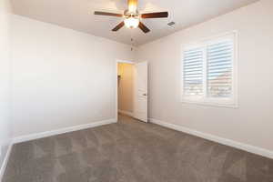 Carpeted spare room with baseboards and a ceiling fan