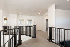 Corridor with an upstairs landing, carpet flooring, recessed lighting, and arched walkways