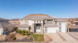 Prairie-style home with stone siding, stucco siding, a mountain view, and concrete driveway