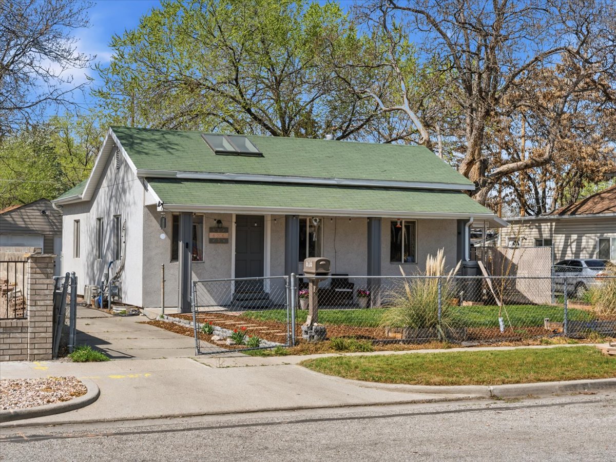 View of front of property featuring stucco siding, a fenced front yard, covered porch, and a gate