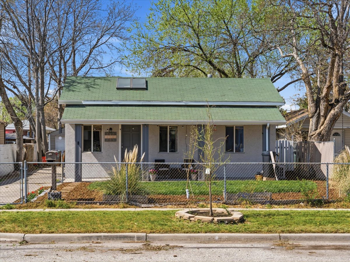 Bungalow-style house with stucco siding, a fenced front yard, covered porch, a gate, and a shingled roof