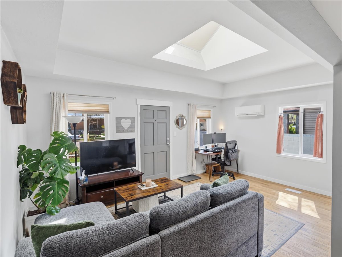 Living room with light wood-type flooring, healthy amount of natural light, a skylight, and a desk
