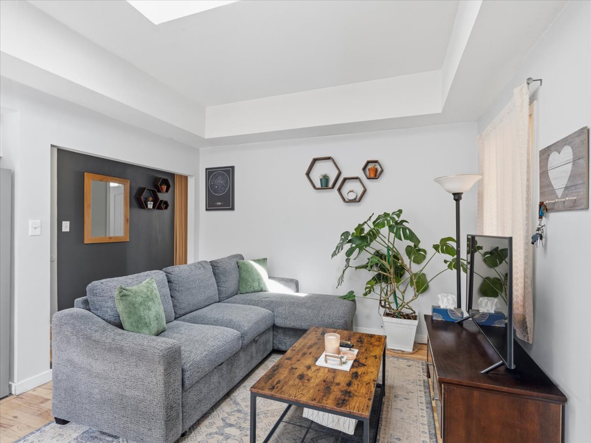 Living area with a raised ceiling and light wood-type flooring