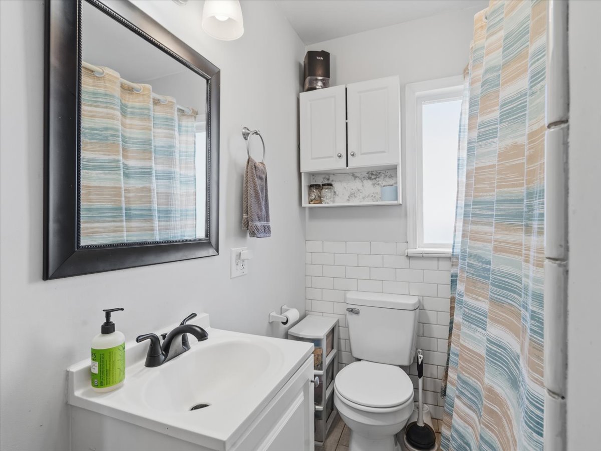 Bathroom featuring curtained shower, tile walls, and vanity