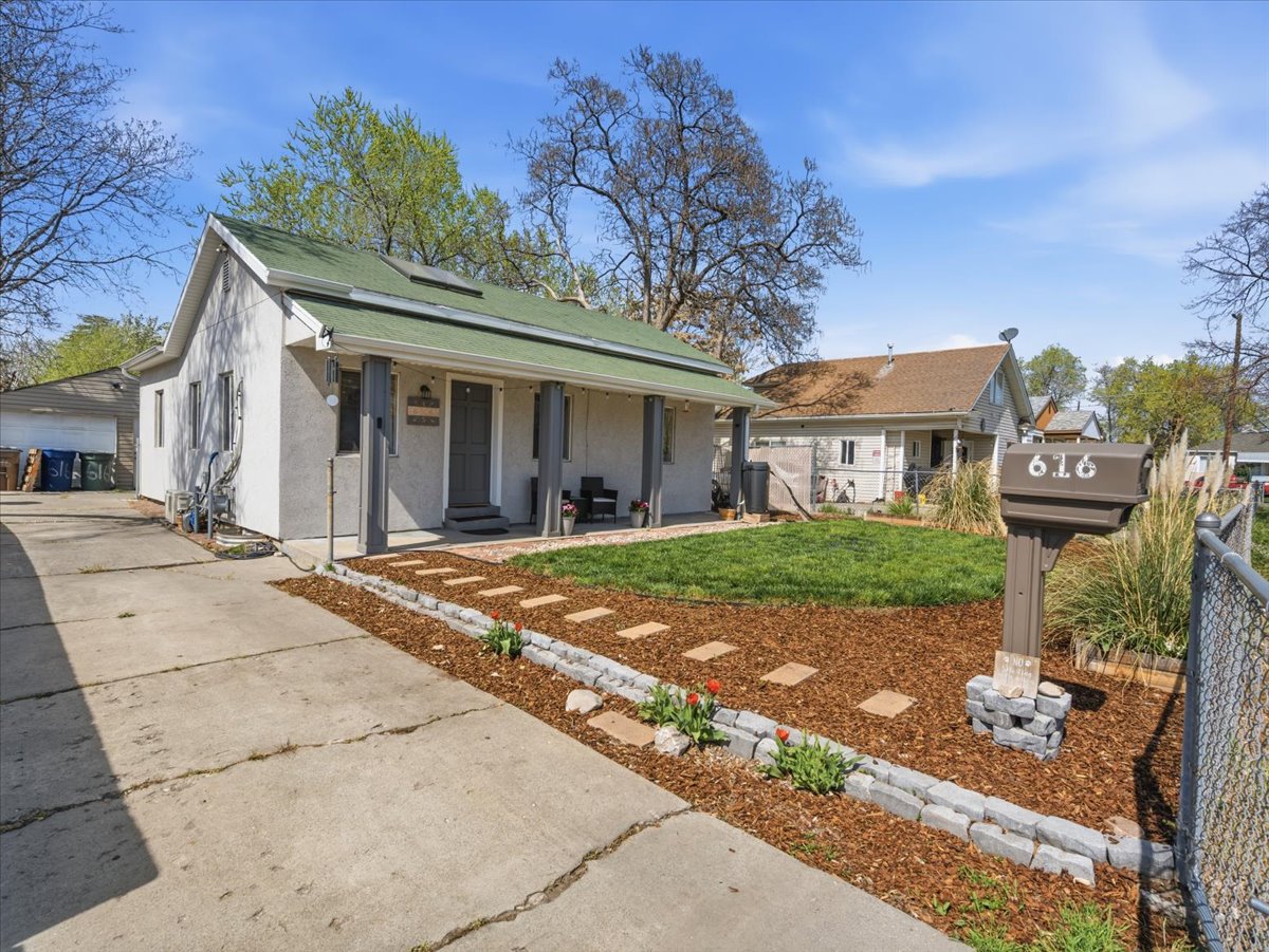 View of front of house featuring roof mounted solar panels, stucco siding, covered porch, and a garage