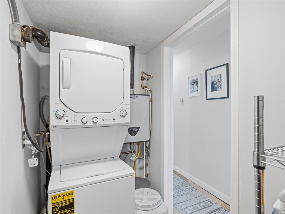 Laundry area with stacked washer and clothes dryer and water heater