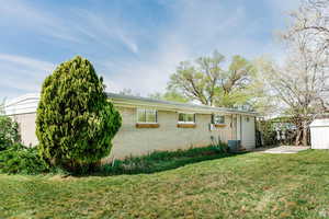 View of front of property with a front lawn, brick siding, and an outdoor structure