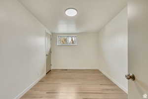 Spare room featuring light wood-style flooring and baseboards
