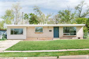 View of front facade featuring a front yard, brick siding, and crawl space