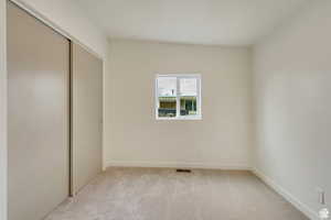 Unfurnished bedroom with light carpet and a closet
