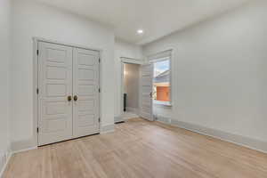 Unfurnished bedroom with light wood finished floors, a closet, and recessed lighting