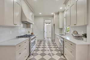 Kitchen with light floors, stainless steel appliances, light stone counters, white cabinets, and recessed lighting