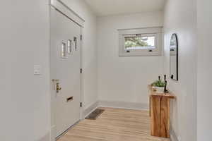 Doorway to outside with wood finished floors and baseboards