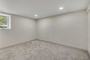 Carpeted spare room with baseboards and recessed lighting