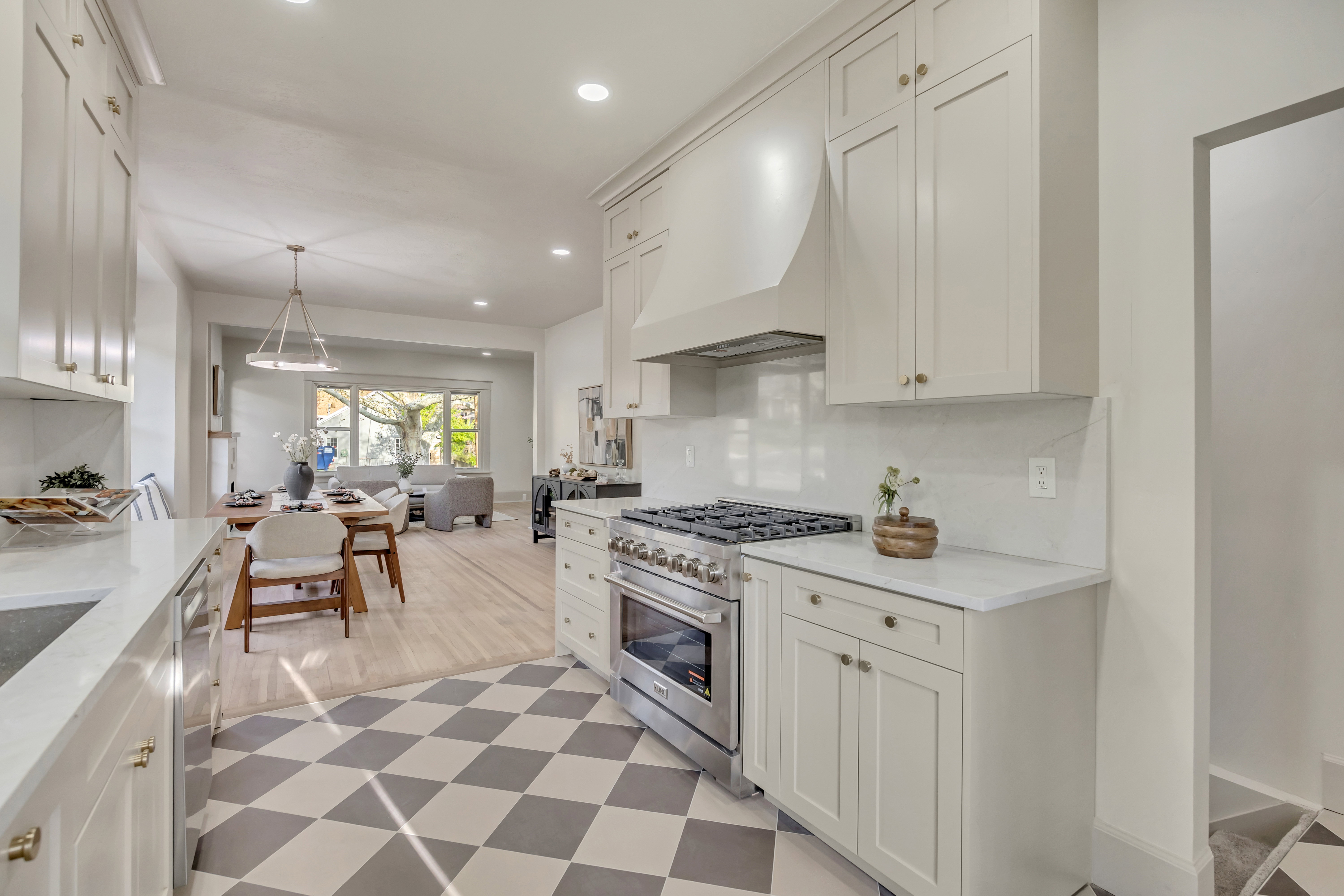 Kitchen with stainless steel appliances, white cabinetry, light stone countertops, and light flooring